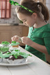 Caucasian girl making St. Patrick's cupcakes