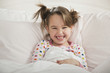 Grinning Caucasian girl laying in bed