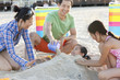 Family burying daughter on beach