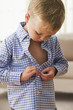 Caucasian boy buttoning his shirt
