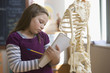 Caucasian girl studying skeleton in classroom