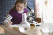 Caucasian girl looking into classroom microscope