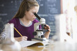Caucasian girl looking into classroom microscope