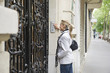 Hispanic woman pressing buzzer on city street