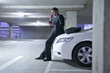 Caucasian businessman sitting on car in parking garage