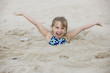 Caucasian girl buried in the sand on beach