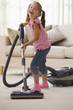 Laughing girl vacuuming living room floor