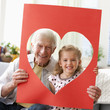 Caucasian grandfather and granddaughter looking through heart-shaped hole