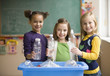 Students recycling plastic bottles in classroom