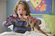 Caucasian boy playing with dinosaurs on bed