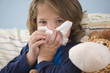 Sick, Caucasian boy blowing nose in bed