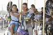Hispanic mother and daughter riding carousel