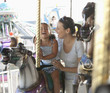 Hispanic mother and daughter riding carousel