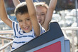 Brother and sister riding amusement park ride