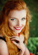 The beautiful red-haired girl poses on a sandy beach