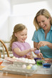Caucasian mother decorating Easter eggs with daughter