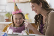 Caucasian mother putting cake icing on daughter's nose