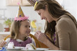 Caucasian mother and daughter eating birthday cake
