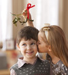 Girl kissing boy underneath mistletoe