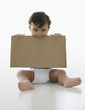 Mixed race baby boy holding piece of cardboard