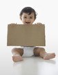Mixed race baby boy holding piece of cardboard