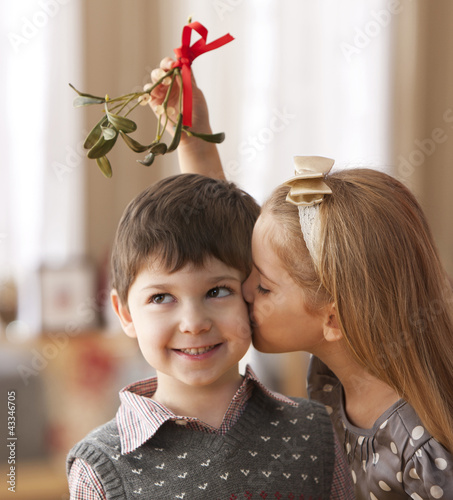 Photo: Girl kissing boy underneath mistletoe Girl kissing boy underneath mistletoe