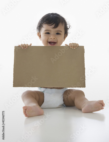 Photo: Mixed race baby boy holding piece of cardboard Mixed race baby boy holding piece of cardboard