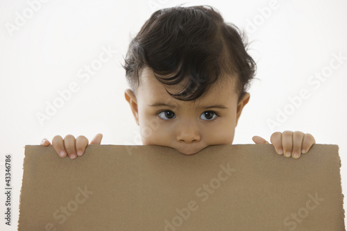 Photo: Mixed race baby boy holding piece of cardboard Mixed race baby boy holding piece of cardboard