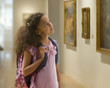 Mixed race girl looking at painting in museum