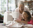 Grandmother teaching granddaughter how to sew