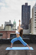 Mixed race woman practicing yoga on rooftop