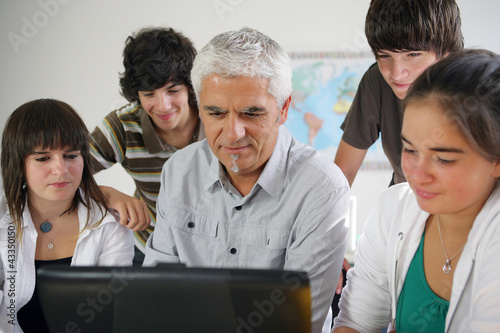 Photo: Teacher and pupils gathered around computer Teacher and pupils gathered around computer