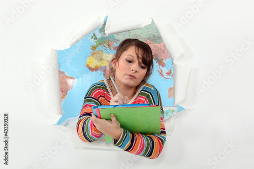 Photo: Girl writing with torn paper in background Girl writing with torn paper in background