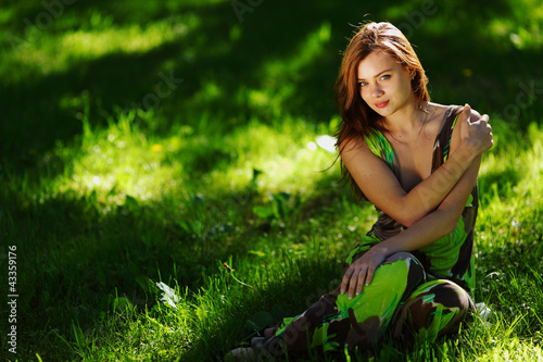 Foto: brunette sitting on green grass brunette sitting on green grass