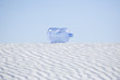 Empty water jug laying on desert sand dune