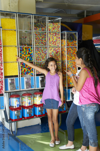 Photo: Hispanic girls looking at candy dispensers Hispanic girls looking at candy dispensers