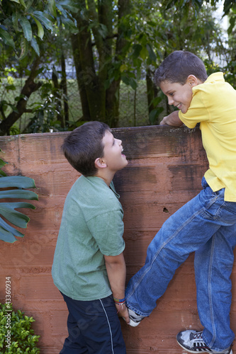 Photo: Hispanic boy helping friend climb wall Hispanic boy helping friend climb wall
