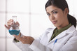 Hispanic scientist holding beaker of liquid