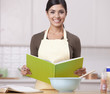 Hispanic woman reading recipe in kitchen