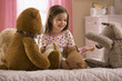 Mixed race girl reading story to stuffed animals