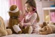 Mixed race girl playing doctor with stuffed animal