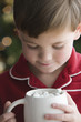 Caucasian boy in pajamas drinking hot chocolate with marshmallows
