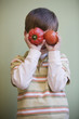 Caucasian boy putting vegetables in front of his eyes