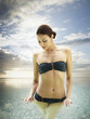 Woman in a bikini standing in the ocean a  tropical luxury resort