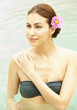 Photo: Close up of woman standing in swimming pool with pink flower in her hair looking out Close up of woman standing in swimming pool with pink flower in her hair looking out