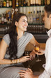 Couple laughing and flirting sitting at the bar drinking a glass of wine