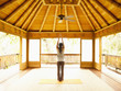 Foto: Rear view of woman standing with arms raised inside yoga and meditation pagoda at a luxury resort Rear view of woman standing with arms raised inside yoga and meditation pagoda at a luxury resort