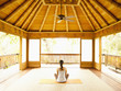 Foto: Rear view of woman sitting in lotus position on floor of yoga and meditation pagoda at a luxury resort Rear view of woman sitting in lotus position on floor of yoga and meditation pagoda at a luxury resort