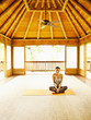 Foto: Woman laughing sitting in lotus position on floor of yoga and meditation pagoda at a luxury resort Woman laughing sitting in lotus position on floor of yoga and meditation pagoda at a luxury resort