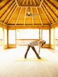 Woman in triangle pose inside yoga and meditation pagoda at a luxury resort